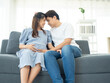 © arlee - A happy Asian couple. Handsome husband and his beautiful wife pregnant sitting on sofa.