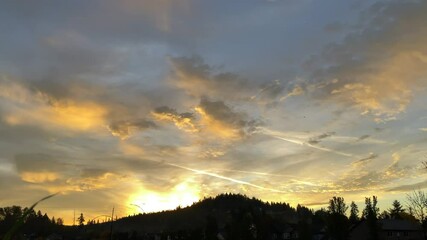 Wall Mural - Sunset time lapse behind tree lined hill bringing beautiful colors to the sky.