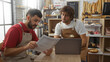 © Krakenimages.com - Men working together as bakers in a bakery interior, holding documents and using a laptop, surrounded by various baked goods and bread on shelves.