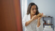 © Krakenimages.com - Young woman in a spa room, brushing her hair with a comb, wearing a white bathrobe, focusing on her beauty routine, under natural light, with wellness products in the background.