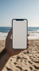 Poster - Hand holding a smartphone with blank white screen on a beach background, perfect for showcasing apps, websites, or social media content with a summer vibe