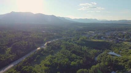 Poster - Drone footage over green fields with lush vegetation and hills under a blue sunny sky