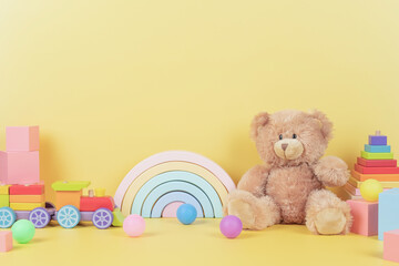 Educational kids toys collection. Teddy bear, wood rainbow, xylophone, wooden educational baby toys on yellow background. Front view