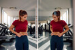© Drazen - Athletic woman feeling dissatisfied with her body fat while looking herself in mirror at health club.