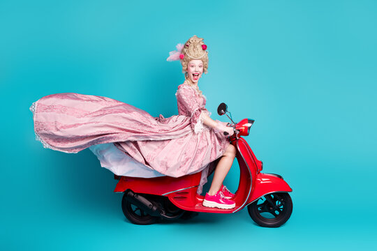 Photo of cheerful charming lady princess driving fast motorcycle isolated on blue color background