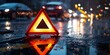 © nakarin - Emergency vehicle warning signal urban street at night reflective safety triangle rainy environment low angle perspective for road safety awareness