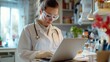 © LifeMedia - A woman in a white lab coat and goggles is focused on her laptop amidst a background of laboratory equipment, embodying dedication and scientific exploration.