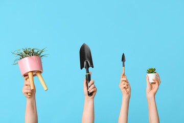 Wall Mural - Female hands with plants and gardening shovels on color background