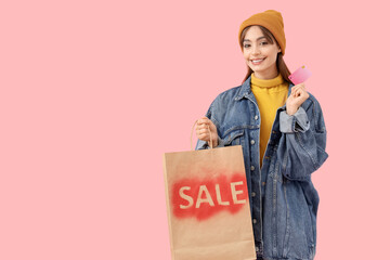 Wall Mural - Young woman with credit card and shopping bag on pink background. Black Friday Sale