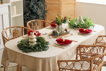 Beautiful festive table setting for Christmas celebration with wreaths in dining room