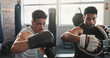 © peopleimages.com - Men, personal trainer and boxing with gloves at gym for training, exercise or workout together. Male person, fitness instructor or coach helping fighter with technique for self defense at health club