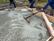© schankz - Three men are working on a concrete slab, using shovels