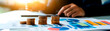 © F-STUDIO - A business-focused image showing stacked coins and graphs, symbolizing financial growth and analysis in a professional setting.