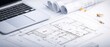 © suraida - Architectural blueprints and engineering planning on laptop in modern office workspace