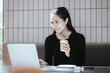 © Witoon - Happy Asian woman working on laptop at coffee shop. Student studying online, surfing the internet.