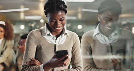 Poster - Black woman, phone and texting by window, office or chat at night with reflection, contact or networking at company. African person, laugh and smartphone on app, happy or reading at creative agency