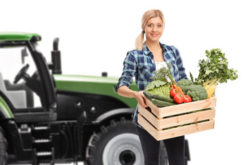 Wall Mural - Female farmer with vegetables standing in front of a tractor