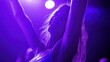 © makappa - A woman with arms raised in the air, dancing under a purple spotlight.