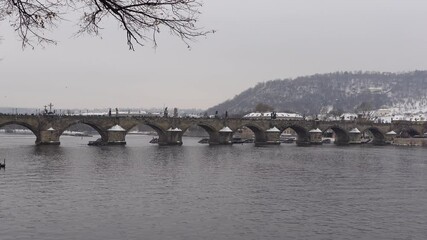 Wall Mural - People walking on Charles Bridge in Prague, Czechia on a grey, snowy winter day