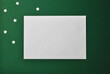 © Irina - A top view of a clean white envelope with some white stars next to it isolated on green background, Christmas concept