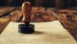 © Manutsanun - A vintage rubber stamp resting on an old document on a wooden table, symbolizing authenticity, authority, and the traditional approval process in business and legal contexts.