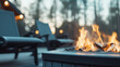 © Kyuubisa - Close up photo of a firepit and outdoor chairs on the deck of a luxury lakehouse. Spot lights and steam rising from the bonfire