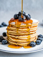 Poster - Pancakes with syrup sprinkled with fresh blueberries and powdered sugar on a white plate