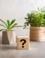 Fototapete - Wooden block with question mark, green plants on backdrop. FAQ and QA. Problem solution.