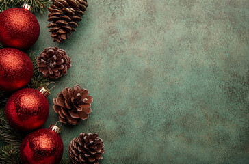 Poster - Red Christmas ornaments and pine cones are arranged on a green background