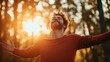 © Dulemegapixel - A man with open arms and a joyful expression stands in a sunlit forest, basking in the warm glow of the sunset, embodying freedom and happiness.