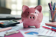 © spyrakot - Business Savings Concept: Piggy Bank Among Office Supplies for Financial Planning and Budgeting