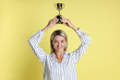 © New Africa - Happy winner with golden trophy cup on yellow background