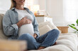 © New Africa - Pregnant woman on sofa at home, closeup