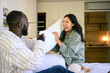 © Dorde - A Black man and an Asian woman share a playful moment with a pillow fight in a cozy bedroom, reflecting joy in their casual attire.