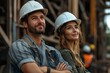 © YURY YUTY - Construction workers smiling confidently at a building site, wearing hard hats.