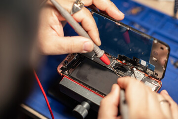 Aufkleber - Expert performs smartphone battery repair with precision tools at a tech workshop