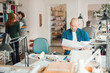 © Geber86 - Mid adult man working in an startup company office with his coworkers behind him
