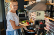 © Geber86 - Young woman filming cooking tutorial in kitchen with fresh vegetables and eggs