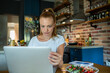 © Geber86 - Woman using laptop on kitchen table while eating healthy meal