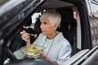 © Davor - Senior nurse eating healthy salad on break in car
