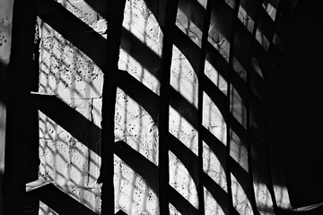 Poster - Shadows cast on a textured wall from a barred window in an abandoned building during late afternoon light. Generative AI