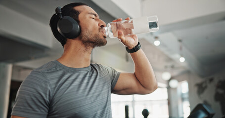 Canvas Print - Fitness, drinking water and man in gym for wellness, health and hydration after workout. Headphones, sports and thirsty person with liquid, minerals and bottle for exercise, training and diet