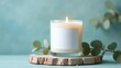 © MarGa - Candle with eucalyptus branches and neutral background. Concept of serenity, mindfulness, and natural minimalism