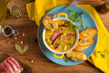 Wall Mural - Traditional Polish pea soup. Prepared with smoked meat. Served in a yellow bowl with croutons. Home made.