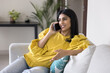 © fizkes - Positive beautiful Indian woman making telephone call, talking on cellphone at home, looking away, speaking on mobile phone, smiling, enjoying leisure, conversation, communication