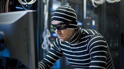 Poster - A person in a striped outfit working on a computer in a server room, depicting a hacker scenario.