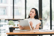 © PRIME STOCK LAB - Focused woman working on tablet in modern office space, surrounded by natural light and greenery, showcasing productivity and creativity