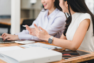 Wall Mural - Collaborative business meeting with two women discussing project details. They are engaged in conversation, sharing ideas, and reviewing documents on wooden table