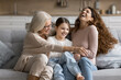 © fizkes - Older granny, her little grandkid and young adult daughter play seated on sofa, laughing, tickling each other, having fun on pastime at home, enjoy priceless time together feeling unconditional love