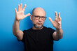© Thales - Bearded, bald man wearing prescription glasses and a black shirt gesturing with his arms to the camera. Confident and calm.